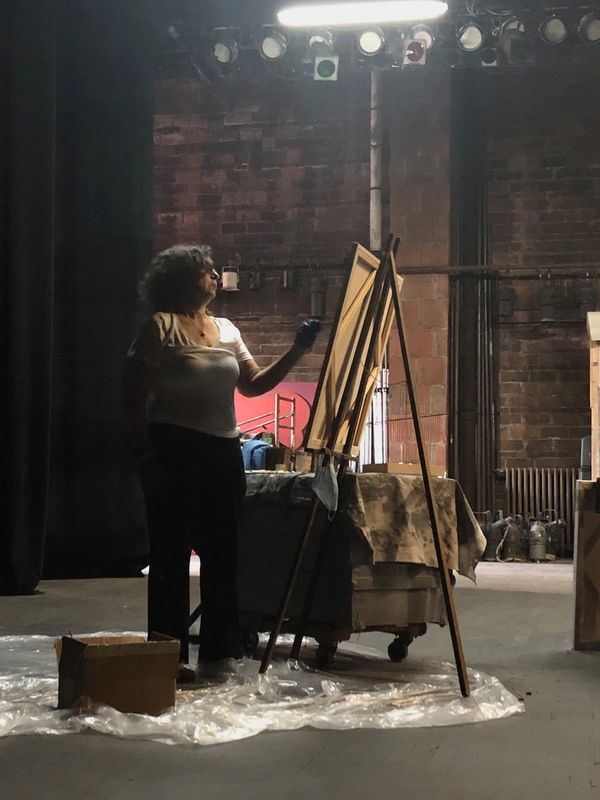 A woman painting on an easel in a studio